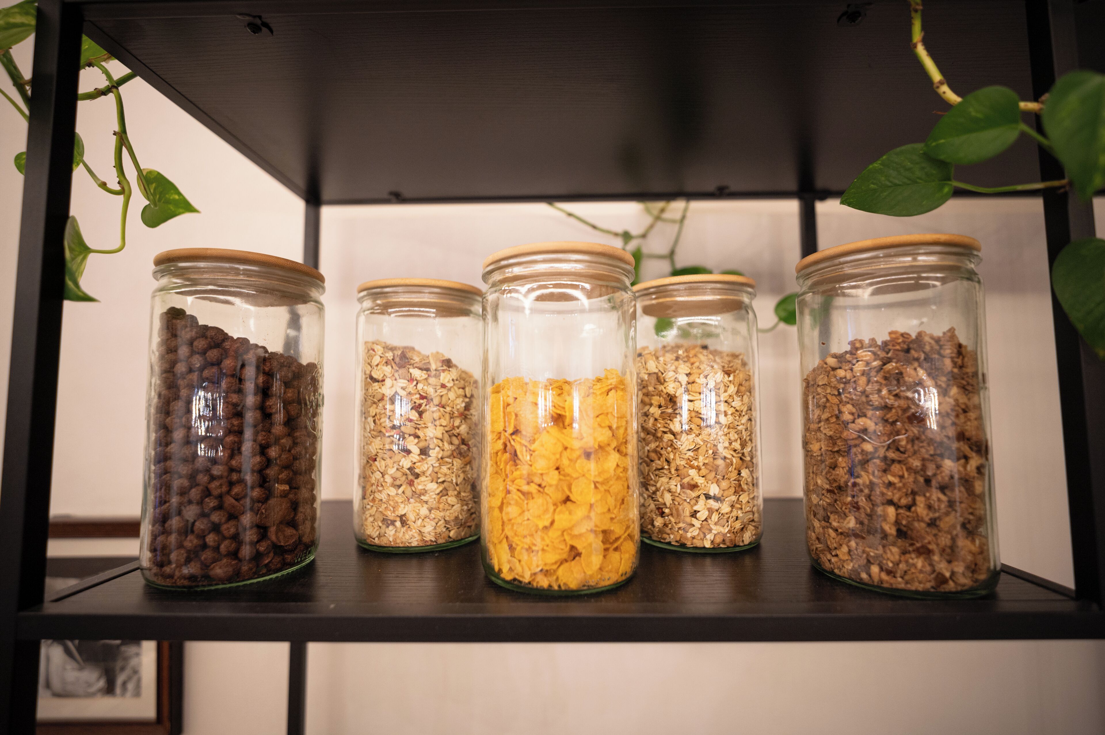 A shelf with five glass jars containing different types of grains.