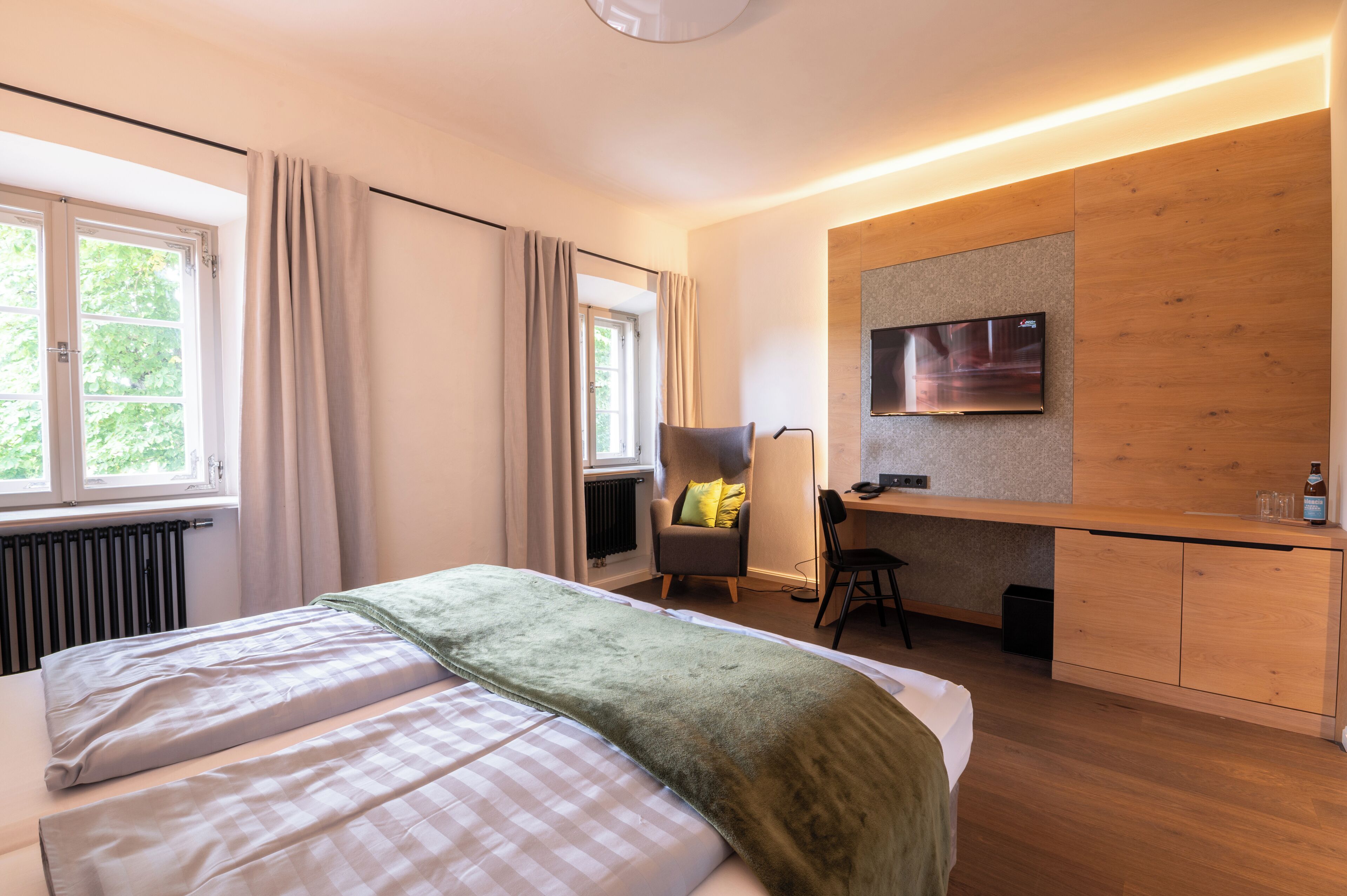 A modern hotel room with a bed, a desk, and a TV.