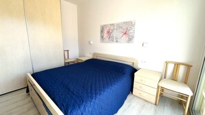 Una camera da letto con un letto, una sedia, un comodino e un armadio.