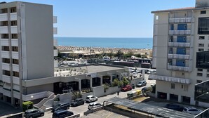 Un edificio a più piani con balconi, un'area di parcheggio e vista sul mare e sulla spiaggia.