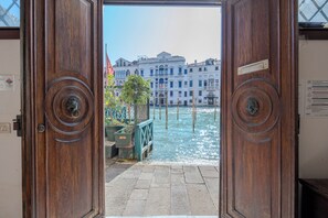 Une porte en bois dotée d’une poignée ronde, qui donne sur un canal bordé de bâtiments.