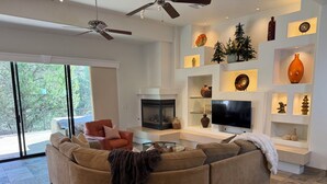 A modern living room with a large sectional sofa, a fireplace, a flat-screen TV, and decorative shelves. - Serene Luxe Prescott Pines Hideaway, Games + Epic Views, Sleep 16+, Fun For All! (Prescott)
