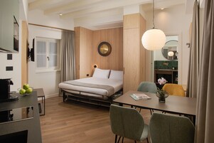 Una moderna camera d'albergo con un letto, un tavolo da pranzo e un angolo cottura.