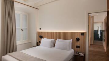 A modern hotel room with a large bed, a nightstand, a wall-mounted clock, and a window with curtains.