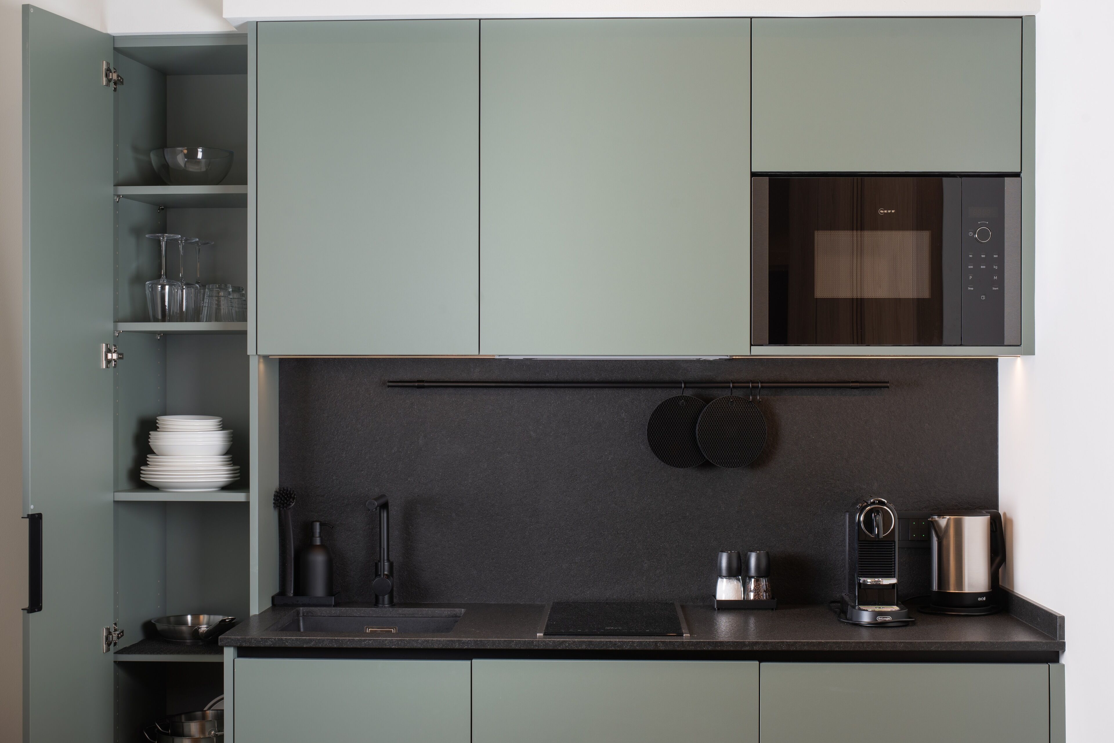 Una cucina moderna con forno a microonde, macchina del caffè e bollitore integrati.