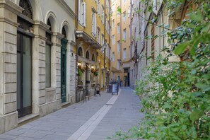 A narrow street with buildings on either side, featuring a mix of architectural styles, including arched doorways and windows with shutters. - AMIRA Ca' Argento Premium Apartments (Trieste)