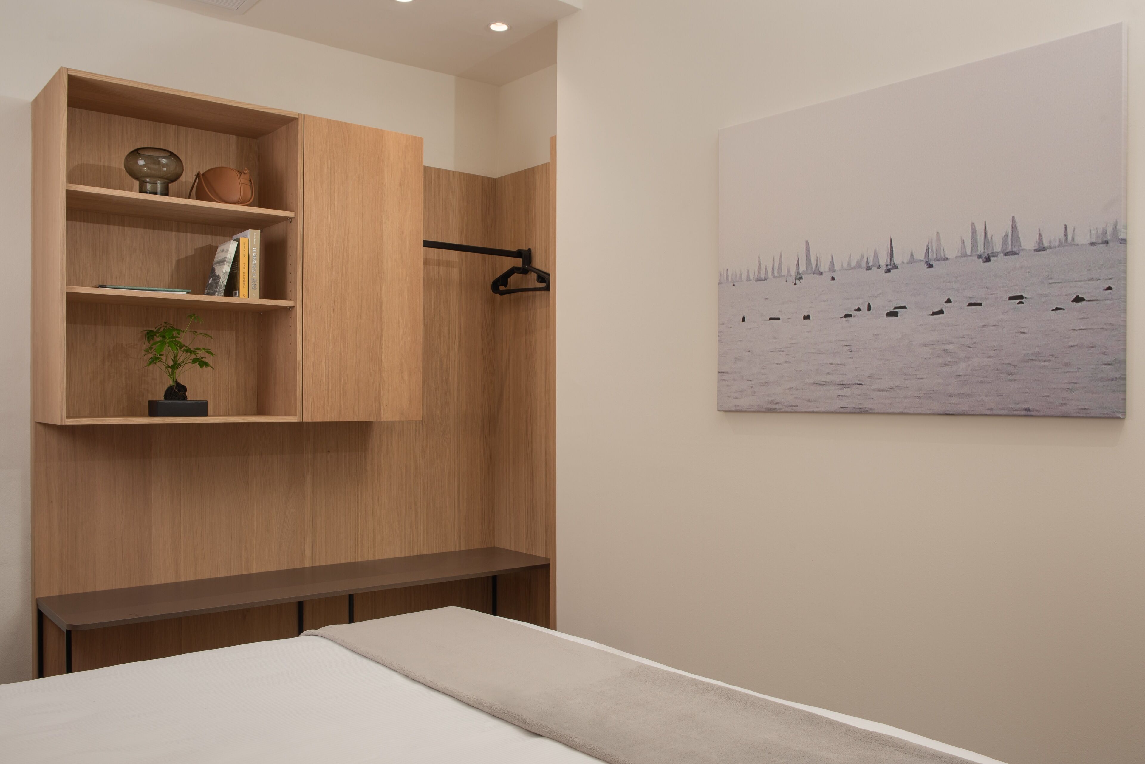 A bedroom with a bed, a wooden wardrobe, a bench, and a painting of a snowy landscape.