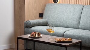 Ett modernt vardagsrum med en grå soffa, ett litet bord med två vinglas och en tallrik mat.