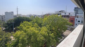 Une vue depuis un balcon donnant sur un paysage urbain, avec des bâtiments et des arbres.
