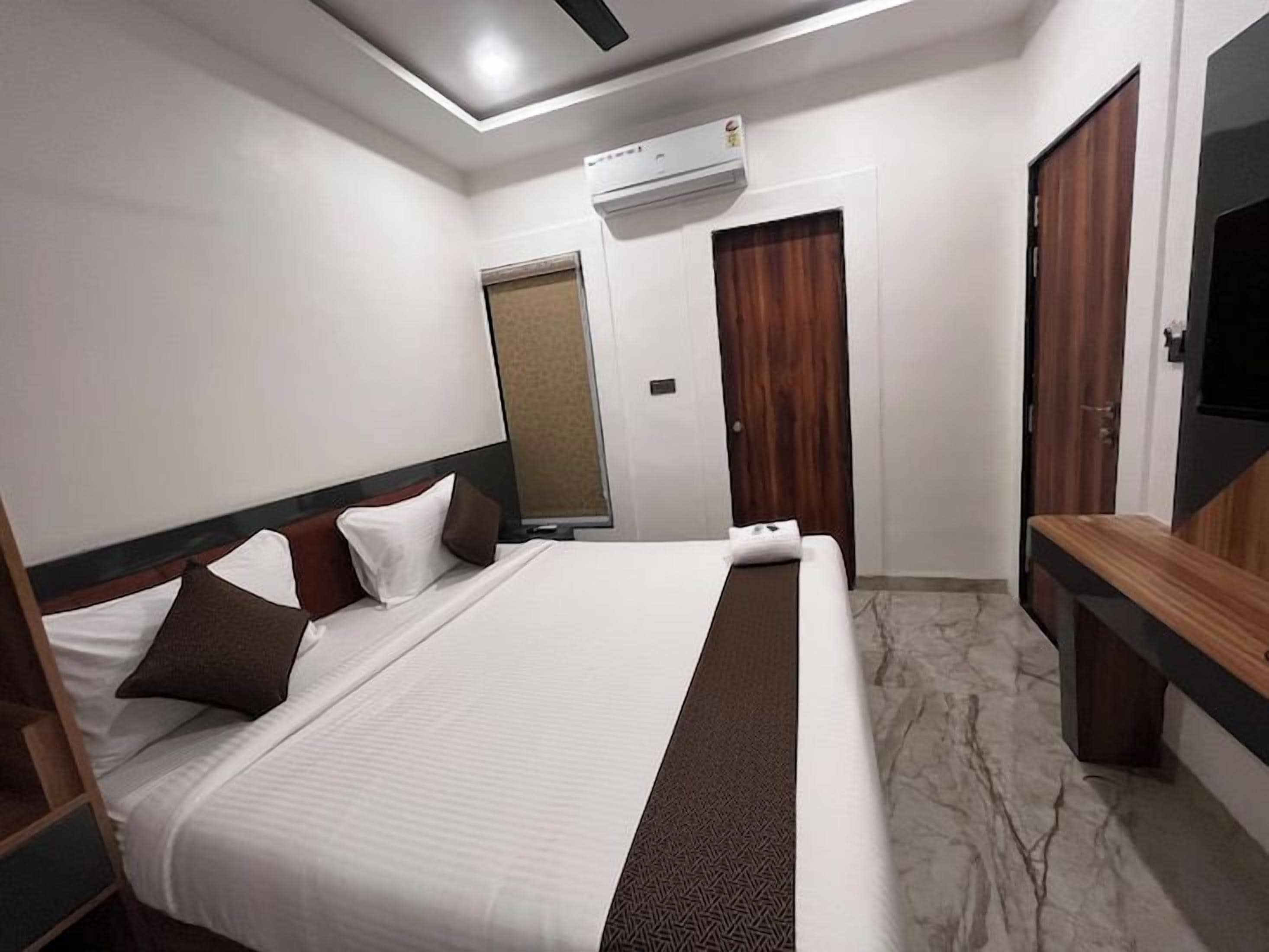 Ein Hotelzimmer mit einem großen Bett, einem Flachbildfernseher, einer Bank und einem Kleiderschrank.