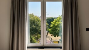 Une pièce dotée d’une grande porte-fenêtre coulissante qui donne sur un espace extérieur agrémenté d’arbres et d’un vélo.
