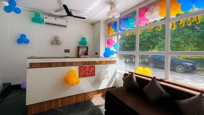 Un espace d’accueil avec un comptoir blanc, un appareil de climatisation et une fenêtre décorée de ballons colorés.