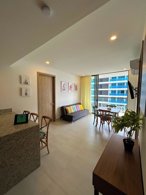 A modern living space with a kitchen area, a sofa, dining table, and chairs.