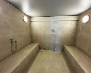 A modern bathroom with two sinks, a shower, and a logo on the wall.