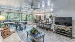 A spacious living room with a sofa, coffee table, TV, and a dining area with chairs and a bar. - Marlandwood Estate - Spacious 5-bedroom house in Temple with outdoor space (Temple)