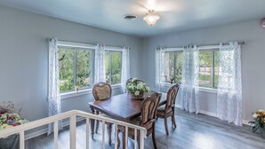 A dining area with a wooden table and chairs, lace curtains, and a ceiling light fixture. - Marlandwood Estate - Spacious 5-bedroom house in Temple with outdoor space (Temple)