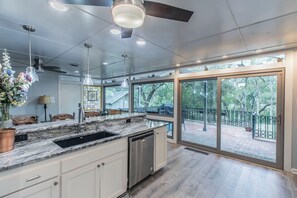 Eine moderne Küche mit einer großen Kochinsel, integriertem Geschirrspüler und einer Schiebeglasdoor zum Patio.