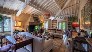 A cozy living room with a fireplace, a dining area, and a bookshelf filled with books.