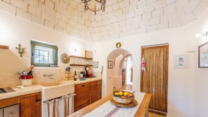 Una cocina con techo de ladrillo, armarios de madera, una ventana y una mesa con una cesta de fruta.