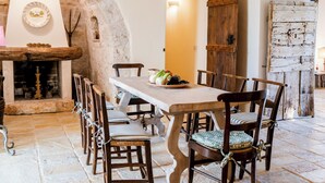 Un comedor rústico con chimenea de piedra, sillas de madera y una mesa larga dispuesta para una comida.