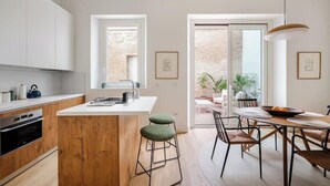 Une cuisine moderne avec un îlot central en bois, des armoires blanches et un coin repas comprenant une table ronde et des chaises.