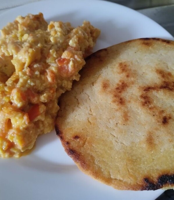 Un plato con huevos revueltos y una porción de pan plano.
