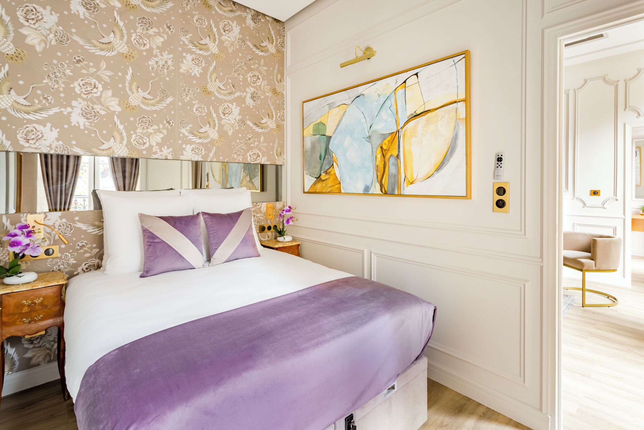 Un dormitorio moderno con una cama grande, una mesita de noche, un espejo y una obra de arte colgada en la pared.