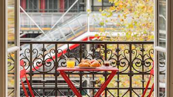 Uma varanda com mesa posta para o café da manhã, incluindo croissants, suco e café.