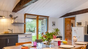 A kitchen with a wooden table set for dining, a dishwasher, and a refrigerator.