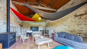A cozy room with a sofa, chairs, a small table, a fireplace, and a hammock.