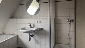 A bathroom with a white sink, a mirror, and a shower.