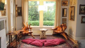 A room with a large window, a wooden chair, a small table, and a red cushion on a patterned rug. - Terrific 5-bedroom house with AC in charming Princeton (Princeton)
