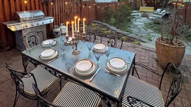 An outdoor dining area with a table set for four, surrounded by chairs, a grill, and string lights. - Terrific 5-bedroom house with AC in charming Princeton (Princeton)