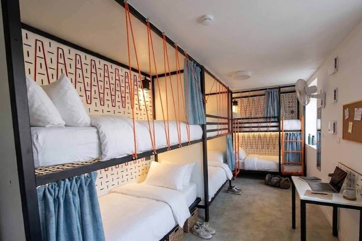 Ein Schlafraum mit Etagenbett, Schreibtisch, Stuhl und Laptop.