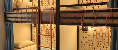 A bunk bed room with a ladder, a patterned headboard, and a blue curtain.