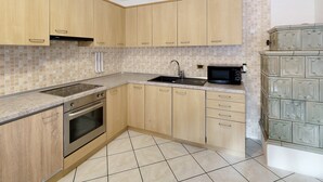 A kitchen with wooden cabinets, a built-in oven, a microwave, and a tiled backsplash.