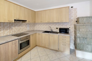 A kitchen with wooden cabinets, a built-in oven, a microwave, and a tiled backsplash.