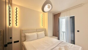 A modern bedroom with a large bed, a mirror, and a unique pendant light.