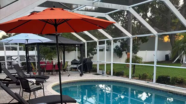 Un área de piscina cubierta con sillones de descanso y sombrillas.