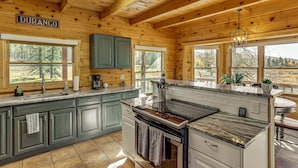 A wooden cabin kitchen with a large island, green cabinets, and a sign that reads "DURANGO". - Stunning San Juan Mtn Views: Cabin Near Skiing! (Durango)