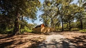 A wooden cabin in a forested area with a gravel path leading to it. - Zen Den Cabin (Houston) (Coldspring)