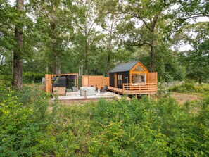 A cabin with a deck, surrounded by dense forest. - Zen Den Cabin (Houston) (Coldspring)