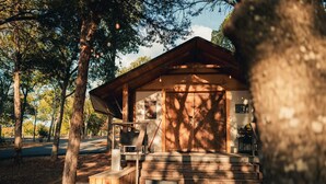 Un chalet rustique avec une façade en bois, une véranda dotée d’un banc et un escalier menant à l’entrée.