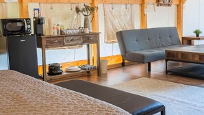 Une chambre confortable dans un chalet, avec un lit, un canapé, une table à manger et un coin cuisine équipé d’un four à micro-ondes, ainsi qu’une pancarte sur laquelle on peut lire « LAC ».