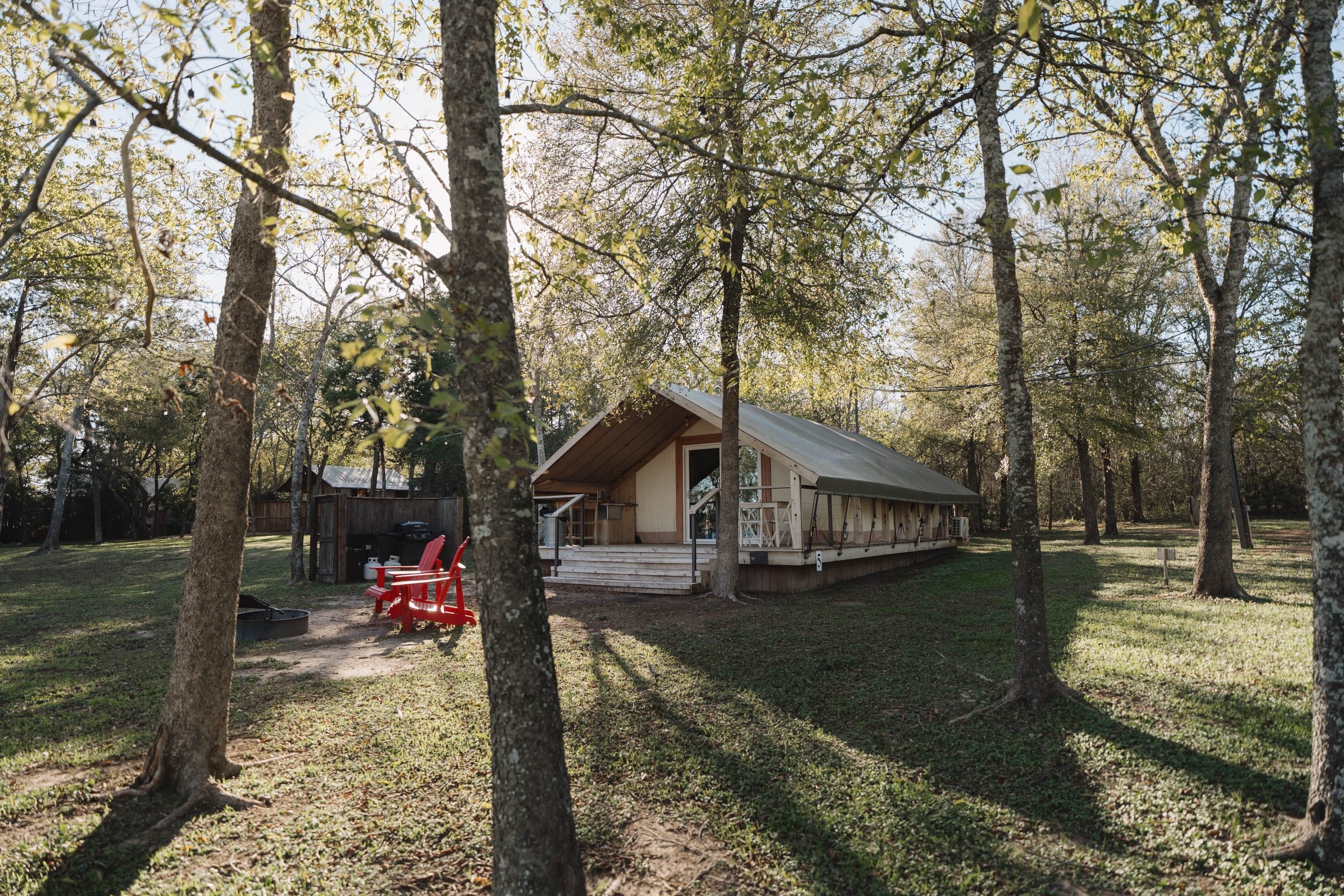 A rustic cabin with a sloped roof, surrounded by trees.