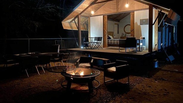 Een gezellig buitgedeelte met een vuurkorf, omringd door stoelen en tafels, onder een overdekte patio met uitzicht op het interieur.