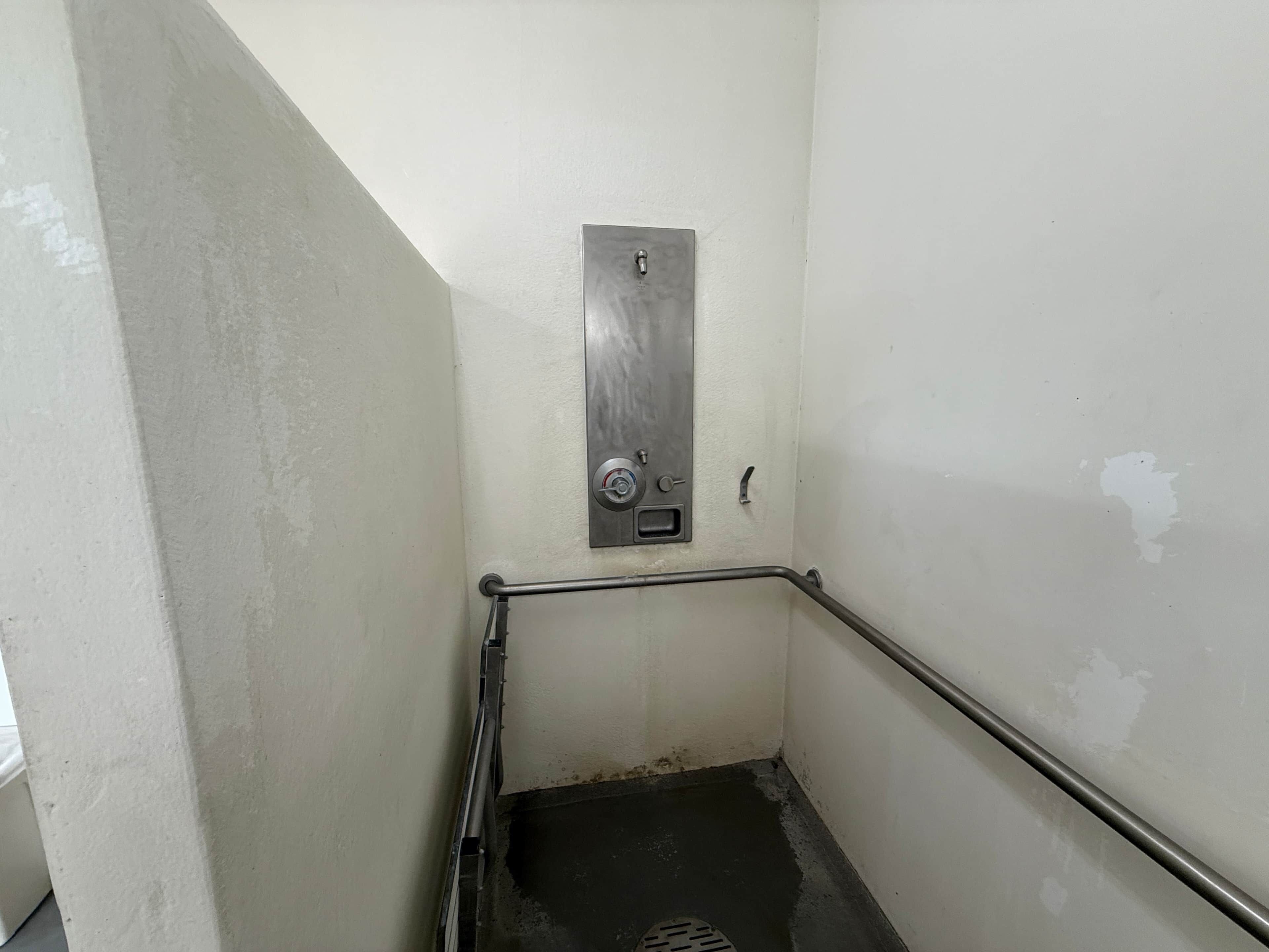 Un escalier étroit doté d’une rampe métallique et d’une porte munie d’un mécanisme de verrouillage.