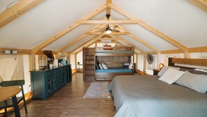 Ein gemütliches Schlafzimmer im Dachgeschoss mit einem Hochbett, einem Schreibtisch und einer Kommode.