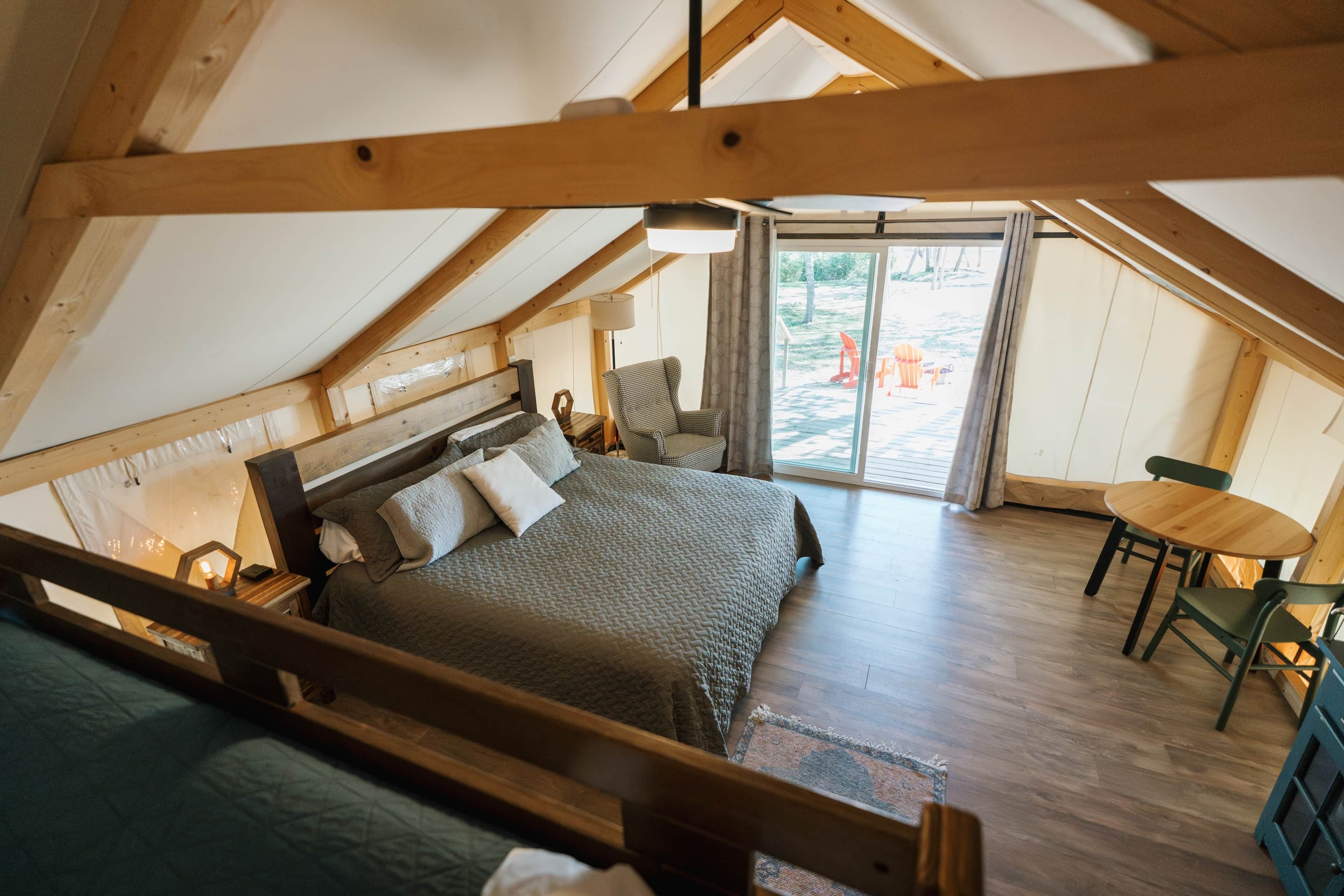 A cozy attic bedroom with a large bed, a chair, and a small table.