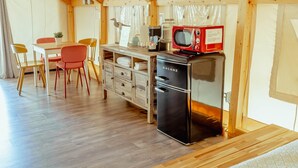Kompakti keittiö, jossa on Galanz-merkkinen jääkaappi, punainen mikroaaltouuni ja puinen ruokapöytä tuoleineen.